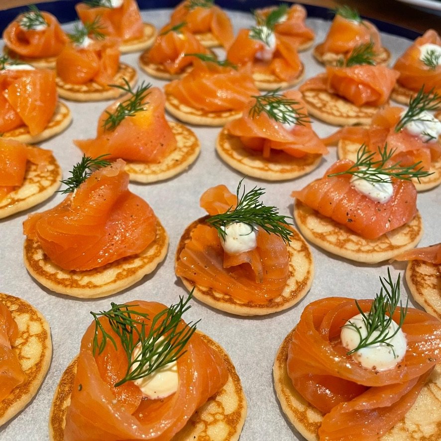 Blini's met gerookte zalm, een toef crème en dille.