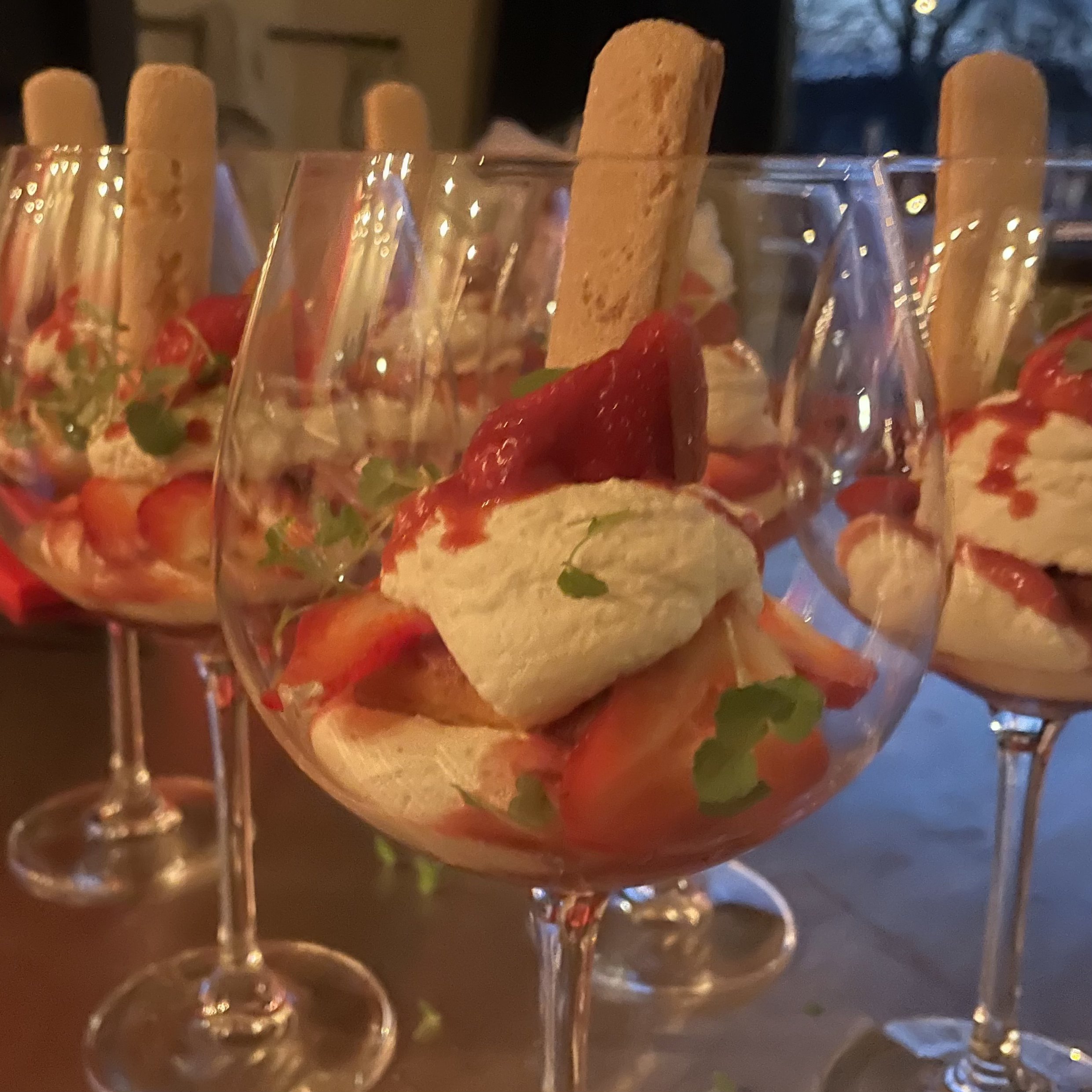 Glazen met aardbeien, mousse en een lange koekjesstaaf als nagerecht.