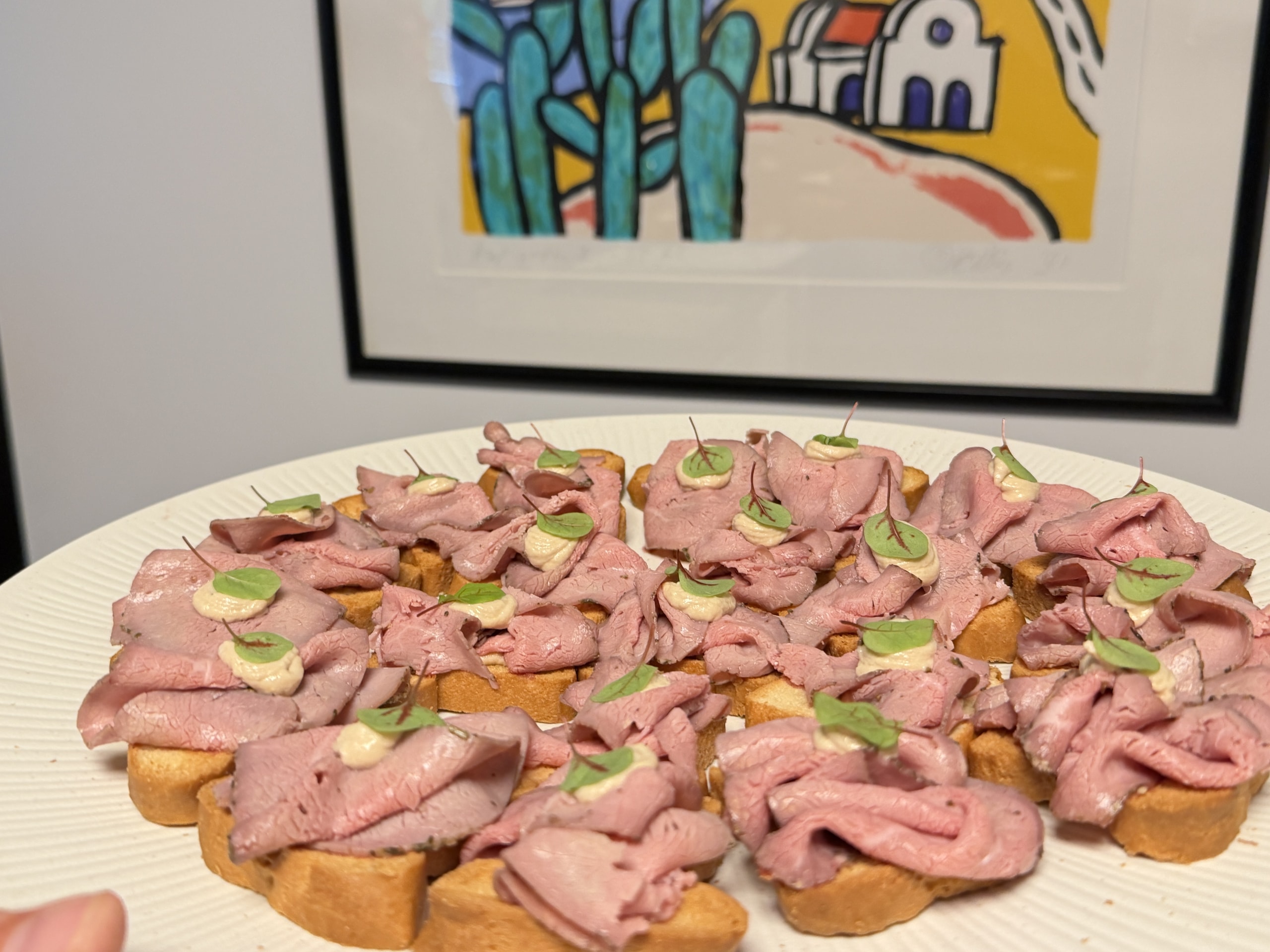 Schaal met crostini's belegd met rosbief en verse kruiden.