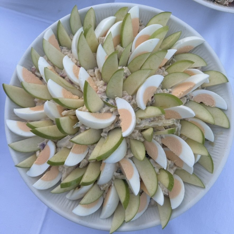 Ronde schaal met partjes gekookt ei en groene appel in een krans, van bovenaf.